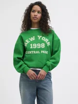 Buzo verde de corte relajado, con cuello redondo, mangas largas y puños elastizados. Presenta un estampado frontal con texto universitario blanco que dice "NEW YORK 1998 CENTRAL PARK".