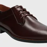 Zapato de vestir formal tipo derby, confeccionado en cuero vacuno color vino con acabado brillante. Presenta cierre mediante cordones al tono, costuras reforzadas y suela de goma resistente.