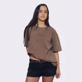Remerón de manga corta, color marrón con efecto gastado, corte holgado y estampado frontal con texto.