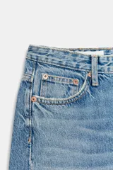 Jeans de tiro medio con diseño de cinco bolsillos y pierna ancha. Presenta un corte recto y holgado con bajo acabado sin costuras y cierre frontal con cremallera y botón metálico.