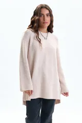 Buzo de tejido de punto en color crudo, con diseño de textura acanalada, cuello redondo, mangas largas holgadas y aberturas laterales en el ruedo.