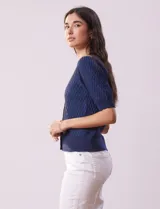 Cárdigan blanco tejido con escote en V, abertura frontal con botones y mangas cortas abullonadas con puño.