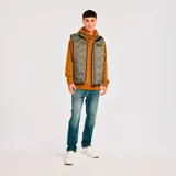 Chaleco acolchado color verde militar con cierre frontal, bolsillos laterales y parche con logo de la marca en el pecho.