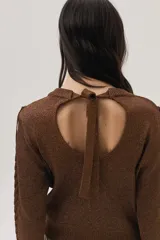 Sweater marrón de tejido de lurex con mezcla de puntos y flecos en el frente. Cuenta con escote abierto en la espalda y lazo.