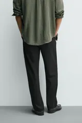 Pantalón de corte recto confeccionado en tejido elástico, con cintura elástica, pliegues frontales, bolsillos laterales y bolsillos traseros de vivo con botón.