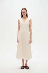 Vestido midi color beige claro, con cuello en V, sin mangas y corte entallado con pinzas.