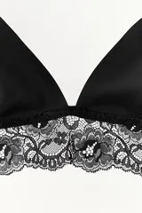 Bralette negro de copa triangular sin aro, con tirantes finos ajustables y un amplio detalle de encaje floral en el bajo.