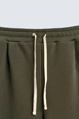 Pantalón de corte wide fit confeccionado en tejido técnico compacto con efecto neopreno. Presenta cintura elástica con cordón ajustable, pliegues frontales, bolsillos laterales y detalle de pliegues en las rodillas con aplicaciones metálicas.