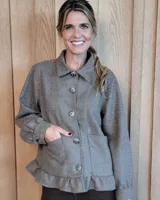Sobrecamisa de pana con diseño de rayas diagonales, cuello clásico, cierre frontal con botones y detalle de volado en el ruedo. Cuenta con bolsillos frontales y mangas largas con puños abotonados.