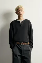 Camiseta relaxed fit de punto negro tejido en hilatura de algodón, con cuello redondo, cierre frontal de botonadura y manga larga con acabado en rib.