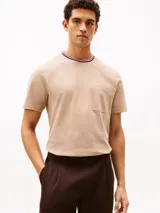 Remera de manga corta confeccionada en tejido de piqué de algodón, con cuello redondo y bolsillo de parche en el pecho. Presenta detalles tricolores en el borde del cuello, característicos de la marca.