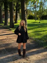 Vestido corto de lino color negro, con silueta amplia y relajada, mangas largas abullonadas y detalle de volado en el ruedo.