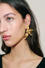 Pendientes metálicos dorados con diseño de flor en relieve y acabado texturizado.