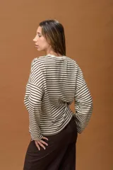 Sweater de punto con diseño de rayas horizontales en color crema y marrón. Presenta un corte holgado, cuello redondo y mangas largas con caída relajada, incorporando hilos de lurex que aportan un brillo sutil.
