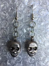 Par de caravanas colgantes plateadas con forma de calavera.