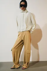Chaqueta de nylon color crudo, con cuello alto, mangas largas, bolsillos delanteros, bajo abullonado con elástico y cierre frontal con botones forrados.