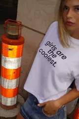 Remera blanca de manga corta, corte cropped y cuello redondo, con estampado frontal en negro que dice "girls are the coolest.".