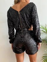 Mono corto negro de lentejuelas con escote en V, mangas largas y abertura en la cintura.
