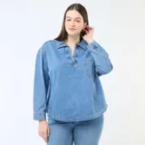 Blusa recta de jean azul claro, con cuello camisero, escote en V con abertura y un bolsillo aplicado en el pecho.
