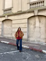 Campera tipo bomber color camel, confeccionada en gamuza, con bordados decorativos en tonos natural y bordó en las mangas y hombros. Presenta cierre frontal y diseño holgado.