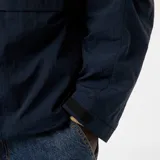 Chaqueta cortavientos azul marino con capucha, cierre frontal y bolsillos con solapa a la altura de la cintura. Presenta un diseño técnico y holgado.