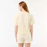 Pijama de dos piezas color amarillo, compuesto por una remera de manga corta con estampa frontal de Simba, Timón y Pumba bajo un arcoíris y la frase "Explore the wild", y un short a rayas sutiles con elástico en la cintura.