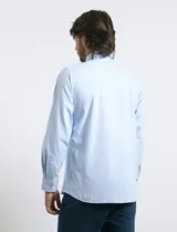 Camisa de vestir color celeste, con cuello mao, manga larga y bolsillo frontal en el pecho.
