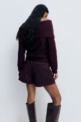 Buzo de punto trenzado con escote estilo off-the-shoulder y cuello ancho acanalado. Presenta mangas largas y terminaciones en punto acanalado en puños y bajo.