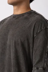 Remera de corte oversize con efecto de lavado gastado, confeccionada en algodón pesado. Presenta cuello redondo, mangas cortas con costuras visibles y un diseño amplio.