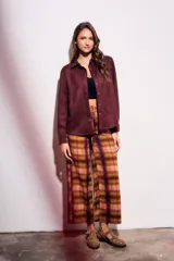 Pantalón de tiro medio y calce recto, confeccionado en poliéster con estampado de cuadros escoceses en tonos burdeos, mostaza, verde oliva y rosado.