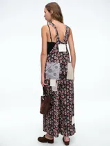 Mono de estilo jardinera con estampado floral y detalles de parches en diferentes texturas y patrones. Presenta un bolsillo frontal en color claro, tirantes ajustables con hebillas metálicas y piernas de corte recto y holgado.