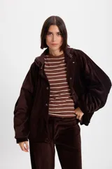 Campera de terciopelo color chocolate, con corte holgado, mangas murciélago y capucha desmontable. Presenta cierre frontal con botones a presión y bolsillos laterales.