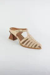 Sandalias de cuero color beige estilo cangrejera con punta fina, diseño de tiras entrelazadas, tira ajustable en el tobillo con hebilla dorada y taco geométrico de madera.