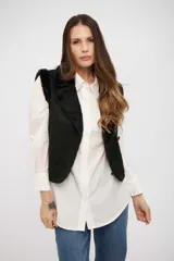 Chaleco negro de gamuza sintética con interior de piel sintética, diseño sin mangas y cierre frontal con botones.