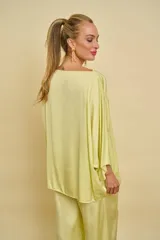 Blusa de satén de seda color verde claro, con cuello bote y mangas amplias tipo murciélago de corte holgado.