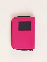 Billetera de nylon color verde esmeralda con cierre perimetral y parche de goma negro con logo en el frente.