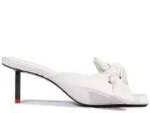Sandalia mule blanca de taco bajo fino, con diseño abierto en la punta y detalle de nudo en la tira superior.