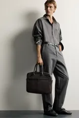 Maletín slim de textura grabada color marrón, con compartimento principal con cierre de cremallera, bolsillo interior para dispositivos electrónicos de hasta 13 pulgadas y bolsillo frontal con cierre. Incluye dos asas de mano y un asa de hombro ajustable y extraíble.