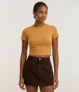 Blusa tipo baby tee de corte ajustado, con cuello redondo y mangas cortas. Confeccionada en tejido de algodón con elastano, ofrece un diseño básico y versátil con estética inspirada en los años 2000.