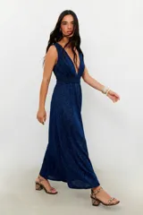 Vestido largo azul oscuro con brillo, escote profundo en V y mangas cortas. Presenta frunces en la cintura que definen la silueta.