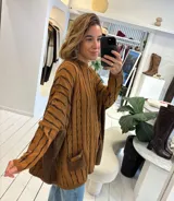 Sweater de tejido de punto con diseño de ochos, color beige, de corte holgado y manga larga con puños ajustados. Presenta dos bolsillos frontales tipo parche con detalle de etiqueta de cuero.
