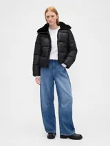 Campera puffer corta de color negro con cierre frontal, cuello con detalle de pelo sintético y diseño acolchado horizontal.