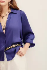 Camisa de poliéster color azul, de corte holgado, con mangas largas y puños elásticos.