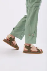 Sandalias planas tipo cangrejeras color verde militar y beige, con suela marrón y tiras ajustables con velcro.