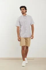 Camisa de manga corta a rayas verticales azules y blancas, con cuello abotonado y cierre frontal con botones marrones.