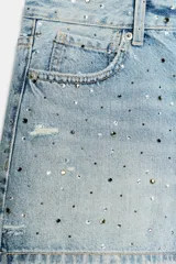Short de denim de tiro medio con cinco bolsillos, cierre frontal con cremallera y botón metálico, adornado con aplicaciones de brillos en la parte frontal.