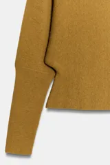 Jersey de punto color mostaza con escote en pico y manga larga con puños ajustados.