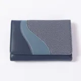 Billetera Faeline color azul con diseño combinado de cuerina lisa, cuerina celeste en una franja curva y tela texturizada tipo denim en el cuerpo principal.