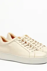 Zapatillas color beige claro, con capellada de cuero suave y acolchado, forro y plantilla de cuero vacuno, y suela de EVA. Tienen una plataforma de 3.8 cm en la parte trasera y 3.2 cm en la delantera.