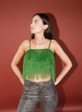 Top corto de tirantes finos, confeccionado completamente en flecos de color verde vibrante.